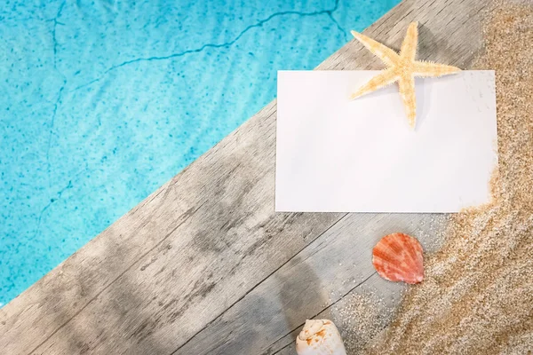Üstünde yazı olmayan bir tatil mektubu. Üstünde deniz yıldızı olan bir havuzun üstündeki tahta kaldırımda. Yazın atmosfer tatili.