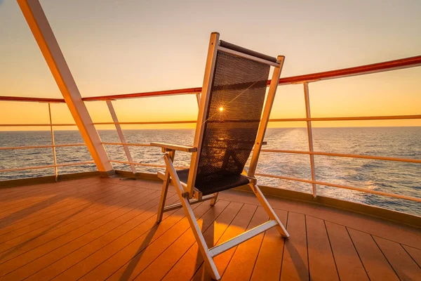View of a deck chair on the deck of a cruise ship at sunset in the wake of the cruise ship. View from the stern of the ship.