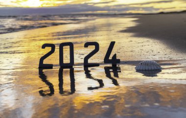Mutlu yıllar 2024: Yeni Yıl 2024 Sahilde gün batımı ve 2024 rakamları denize yansıyan konsept.