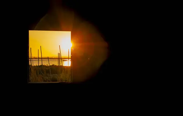 漁小屋の窓からカマルグの池の夕日を見る 保護された自然保護区 ロイヤリティフリーのストック画像