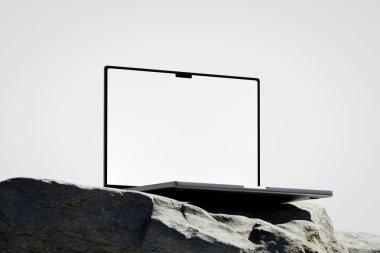 Açılan dizüstü bilgisayarlı bir sahne, kayanın üzerinde beyaz boş bir ekran. 