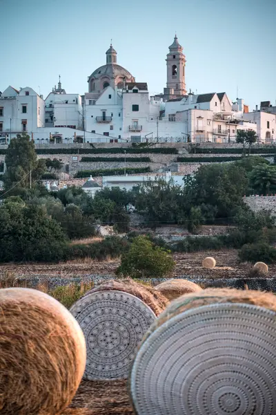 Puglia İtalya 'da Locorotondo' da güneş doğuyor. Önünde saman ambarları var.