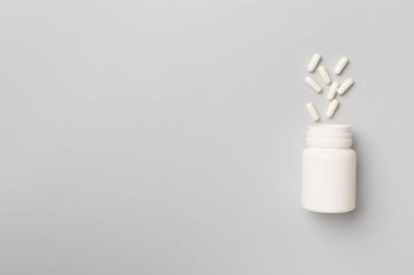 Arka planda haplar olan beyaz şişe..