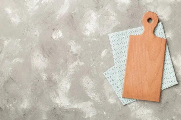 stock image Cutting board with towel on concrete background, top view.