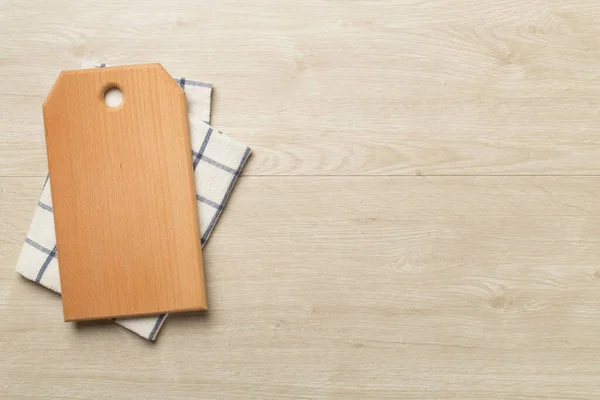 stock image Cutting board with towel on wooden background, top view.