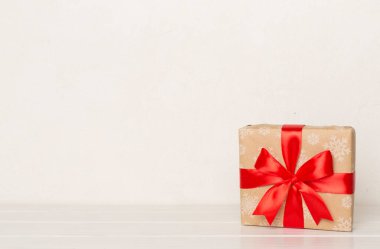 Kırmızı kurdeleli hediye kutusu ışık masasında..