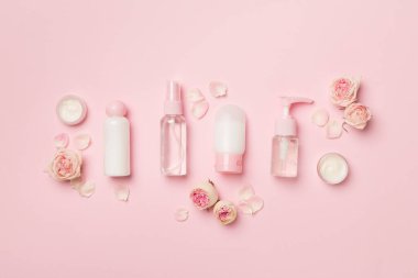Set of small cosmetic bottles on color background, top view.