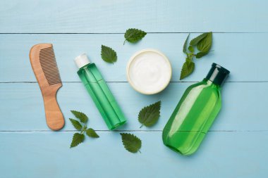 Ahşap arka planda ısırgan otu özlü şampuan ve saç maskesi.