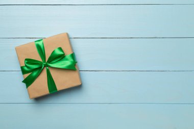 Yeşil kurdeleli hediye kutusu ahşap arka planda, üst manzara.