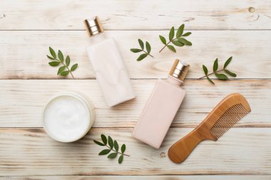 Bitkisel özlü şampuan ve saç kremi ve ahşap arka planda tarak..