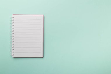 Renk arkaplanı üzerine pembe defter, üst görünüm.