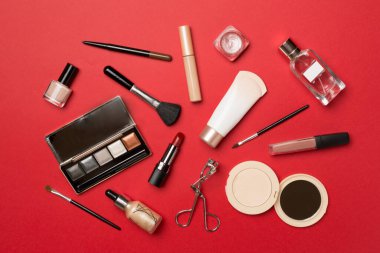Different makeup products on color background, top view.