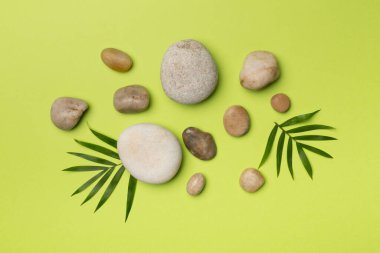 Tahta arka planda kaplıca taşları ve yapraklar, üst manzara.