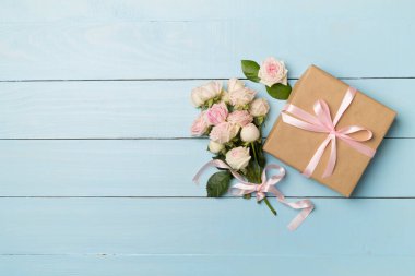 Hediye kutusu ve gül çiçekleri ahşap arka planda, üst manzara.