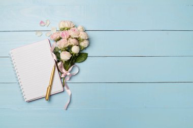 Ahşap arka planda defter ve gül çiçekleri, üst manzara.