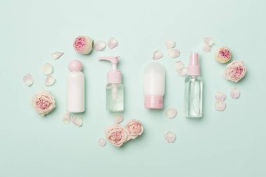 Set of small cosmetic bottles on color background, top view.