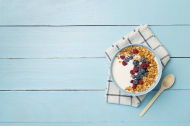 Bowl with granola, yogurt and fresh berries on wooden background, top view.