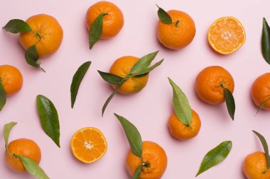 Renkli arka planda taze mandalinalarla yatıyordu. Üst görünüm.