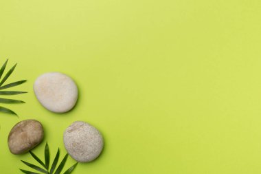 Tahta arka planda kaplıca taşları ve yapraklar, üst manzara.