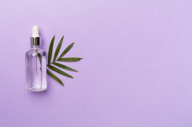 Cam şişede yüz serumu. Arka planda yeşil yapraklar, üst manzara..