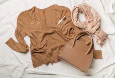 Beyaz çarşafın üzerinde kadın kıyafetleriyle yatıyordu.,