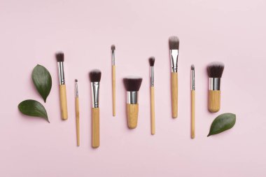 Natural biodegradable makeup brushes on color background, top view