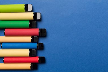 Disposable electronic cigarettes on color background, top view