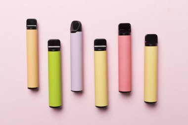 Disposable electronic cigarettes on color background, top view