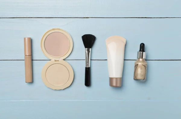 Makeup products for skin tone on wooden background, top view.