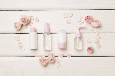 Set of small cosmetic bottles on wooden background, top view.