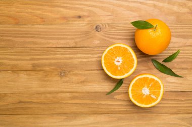 Flat lay with fresh oranges and leaves on wooden background