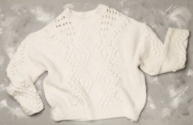 Sweater and winter hat withmittens on light background, top view