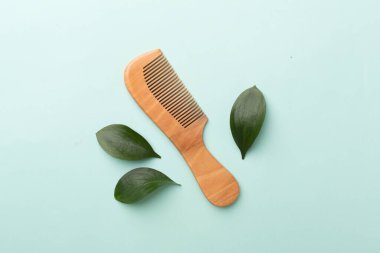 Hair comb with green leaves color on background. Top view