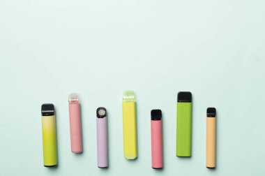 Disposable electronic cigarettes on color background, top view