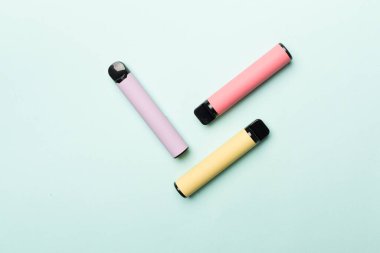 Disposable electronic cigarettes on color background, top view