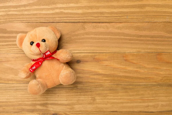 Cute teddy bear on wooden background, top view