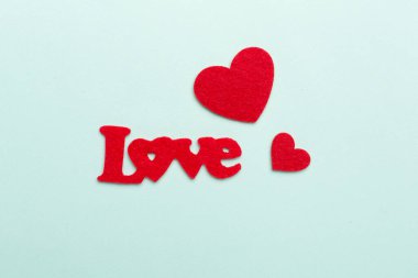 Felt word love with hearts on color background, top view