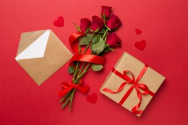 Valentines day gift box with red roses on color background, top view