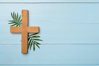 Palm branches and cross on wooden background, top view. Palm Sunday concept.