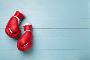 Red boxing gloves on wooden background, top view.