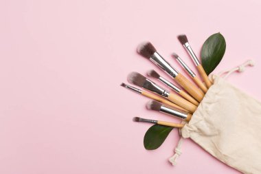 Natural biodegradable makeup brushes on color background, top view