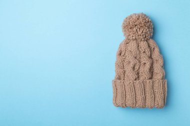 Brown winter hat with pompon on color background. Top view.
