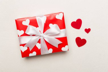 Gift box with hearts on concrete background, top view