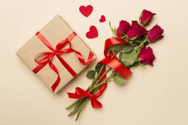 Valentines day gift box with red roses on color background, top view