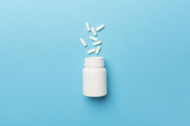 Arka planda haplar olan beyaz şişe..