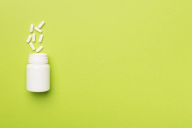 Arka planda haplar olan beyaz şişe..