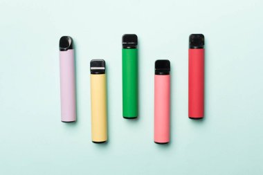 Disposable electronic cigarettes on color background, top view