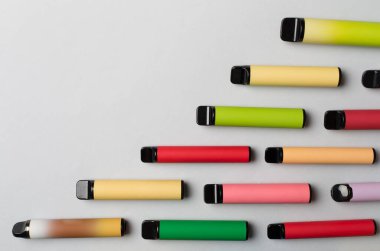 Disposable electronic cigarettes on color background, top view