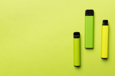 Disposable electronic cigarettes on color background, top view