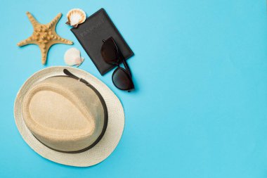 Renkli arka planda şapka, pasaport ve deniz kabukları, üst görünüm.